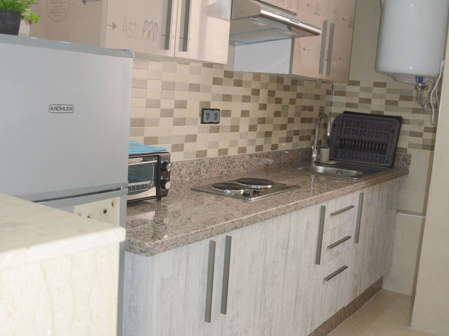 Una cocina con horno empotrado, microondas, tostadora y lavabo.