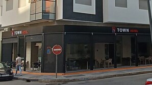 Un edificio moderno con un cartel de Town Hotel, que presenta fachada de vidrio y una paleta de colores blanco y negro.