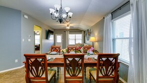 A dining area with a chandelier, wooden chairs, and a table set for four.