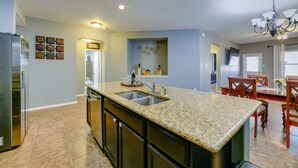A modern kitchen with granite countertops, stainless steel appliances, and a dining area with wooden chairs.