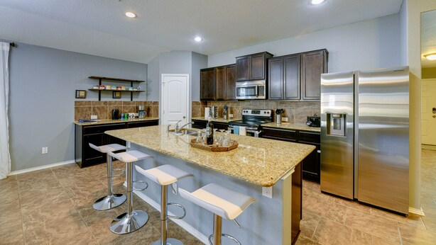 A modern kitchen with granite countertops, stainless steel appliances, and a central island with bar stools.