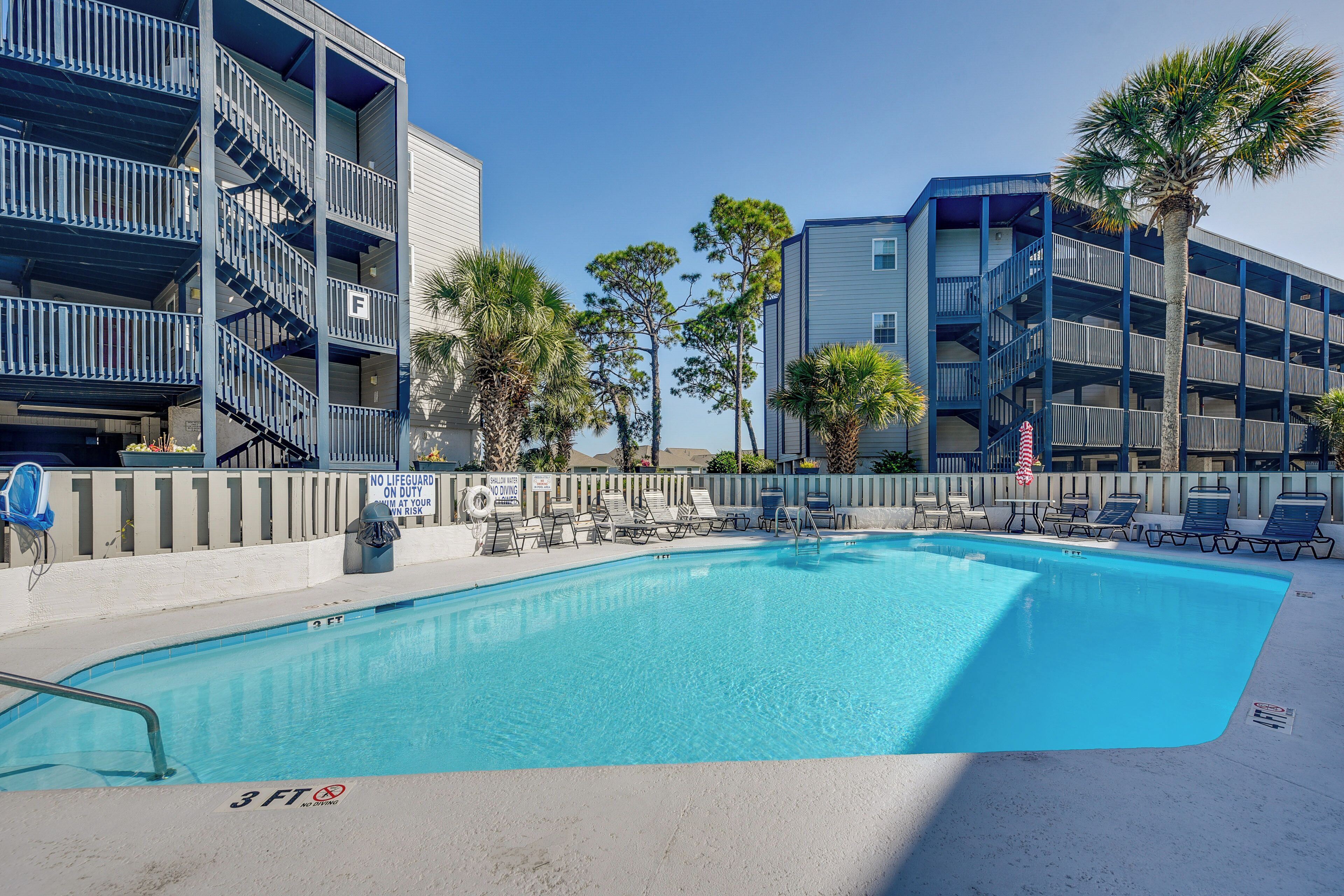 A swimming pool with lounge chairs, a lifeguard stand, and a sign indicating no lifeguard on duty.