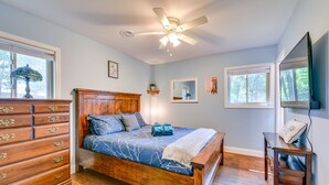 Ein Schlafzimmer mit einem hölzernen Bett, einem Schminktisch, einem Deckenventilator und Fenstern.