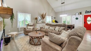 A spacious living room with a high ceiling, a large window, and a red door. - Smoky Mtn Home w/ Hot Tub: 10 Mi to Dollywood! (Sevierville)