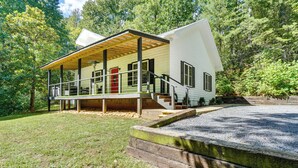 A single-story house with a covered porch, a red door, and a gravel driveway. - Smoky Mtn Home w/ Hot Tub: 10 Mi to Dollywood! (Sevierville)