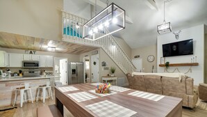 A spacious kitchen with a central island, a staircase leading to an upper level, and a mounted television on the wall. - Smoky Mtn Home w/ Hot Tub: 10 Mi to Dollywood! (Sevierville)