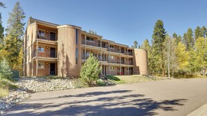 Un immeuble à plusieurs étages doté de balcons, d’une allée et entouré d’arbres.