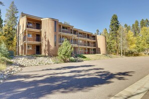 Un immeuble à plusieurs étages doté de balcons, d’un chemin pavé et entouré d’arbres.