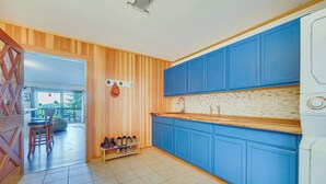 Une cuisine avec des meubles de couleur bleue, un plan de travail en bois et un sol carrelé.
