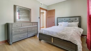 Un dormitorio con cama, cómoda y puerta que da a otra habitación.