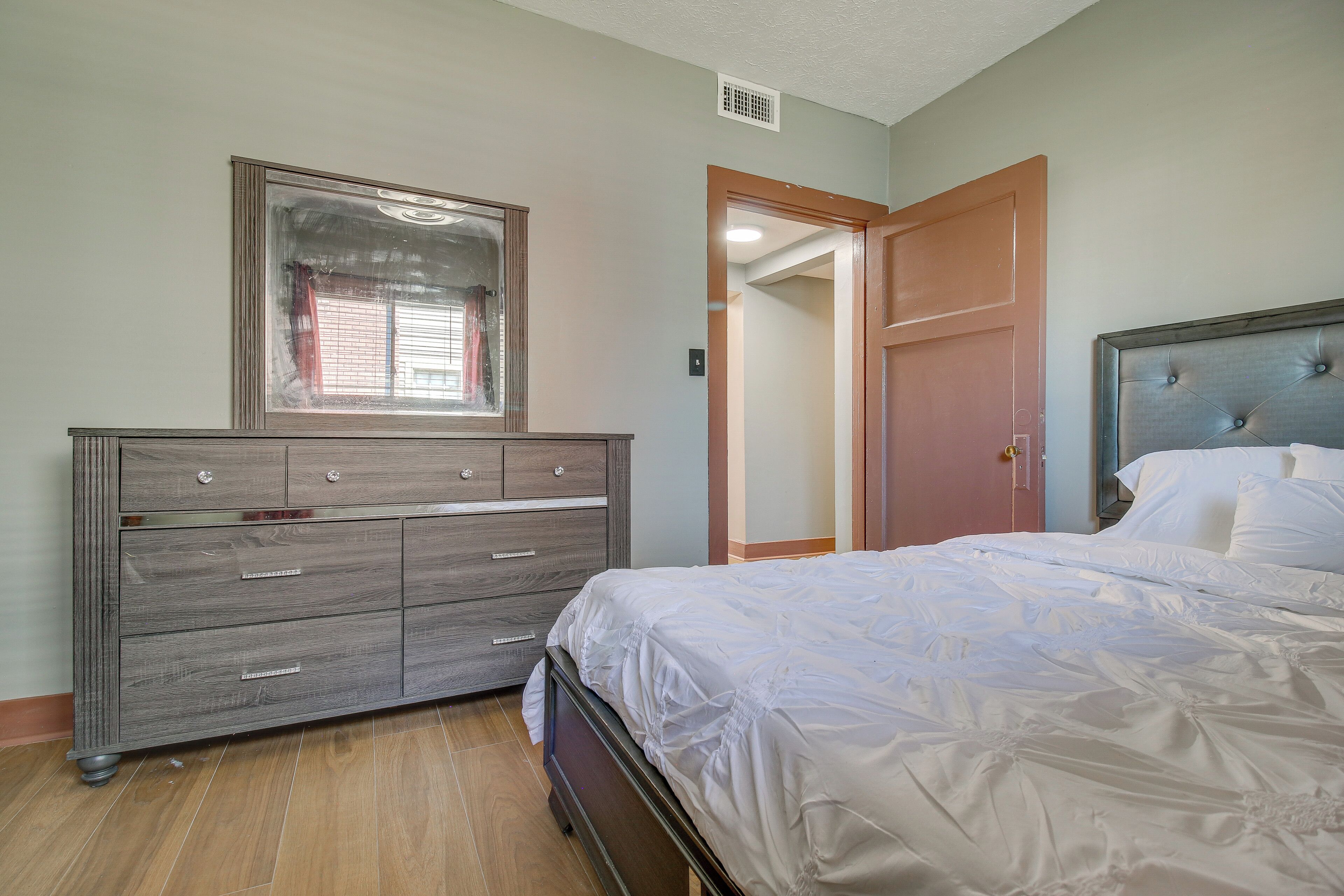 Un dormitorio con cama, cómoda y espejo.