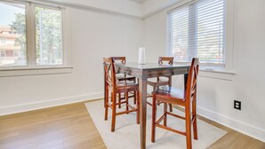 Un comedor con una mesa de vidrio, sillas de madera y un tapete blanco.