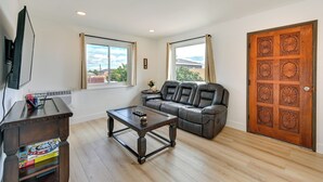A living room with a leather sofa, a wooden coffee table, and a wooden cabinet with books. - Sunny San Diego Home w/ Private Yard & Grill! (San Diego)