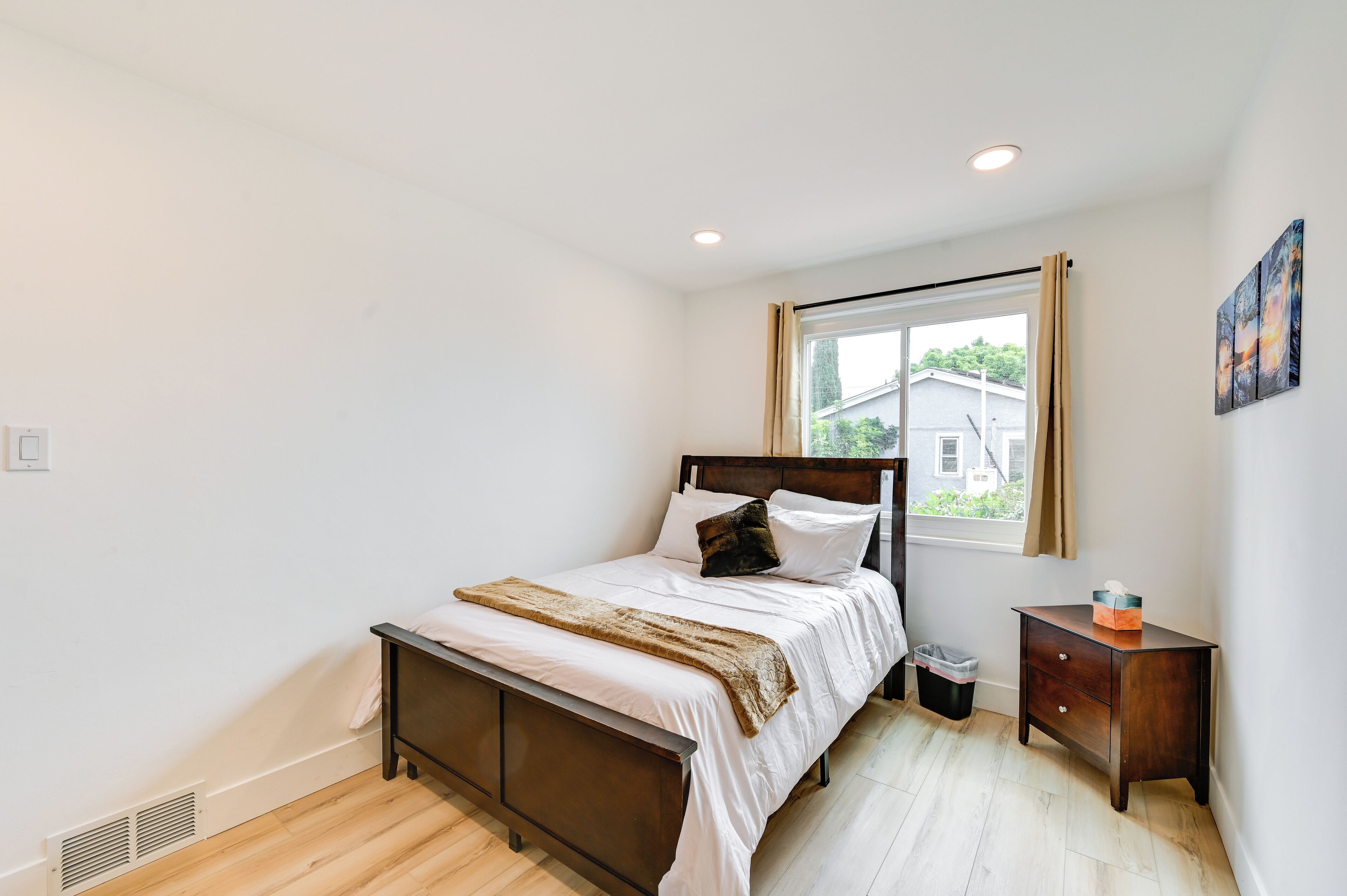 Un dormitorio con cama, mesita de noche, ventana y vistas al exterior.