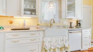 A kitchen with white cabinets, a sink, and a countertop with various items.