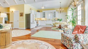 A spacious living room with a large floral sofa, a round coffee table, and a dining area with a table and chairs.