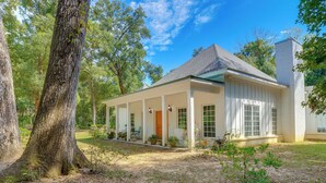 A single-story house with a covered porch, surrounded by trees.