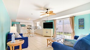 A living room with a blue sofa, a wooden coffee table, and a TV in the background. - Pawleys Island Retreat (Pawleys Island)