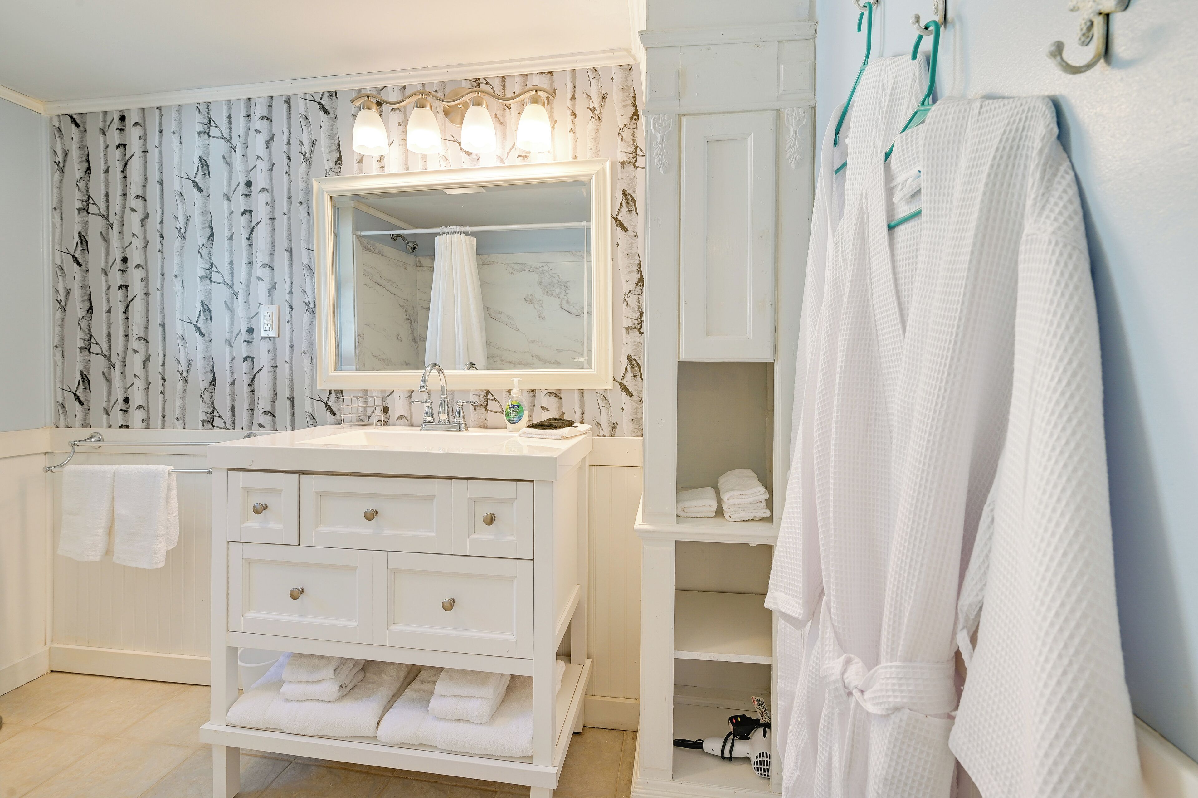 A bathroom with a white vanity, a large mirror, and a towel rack.