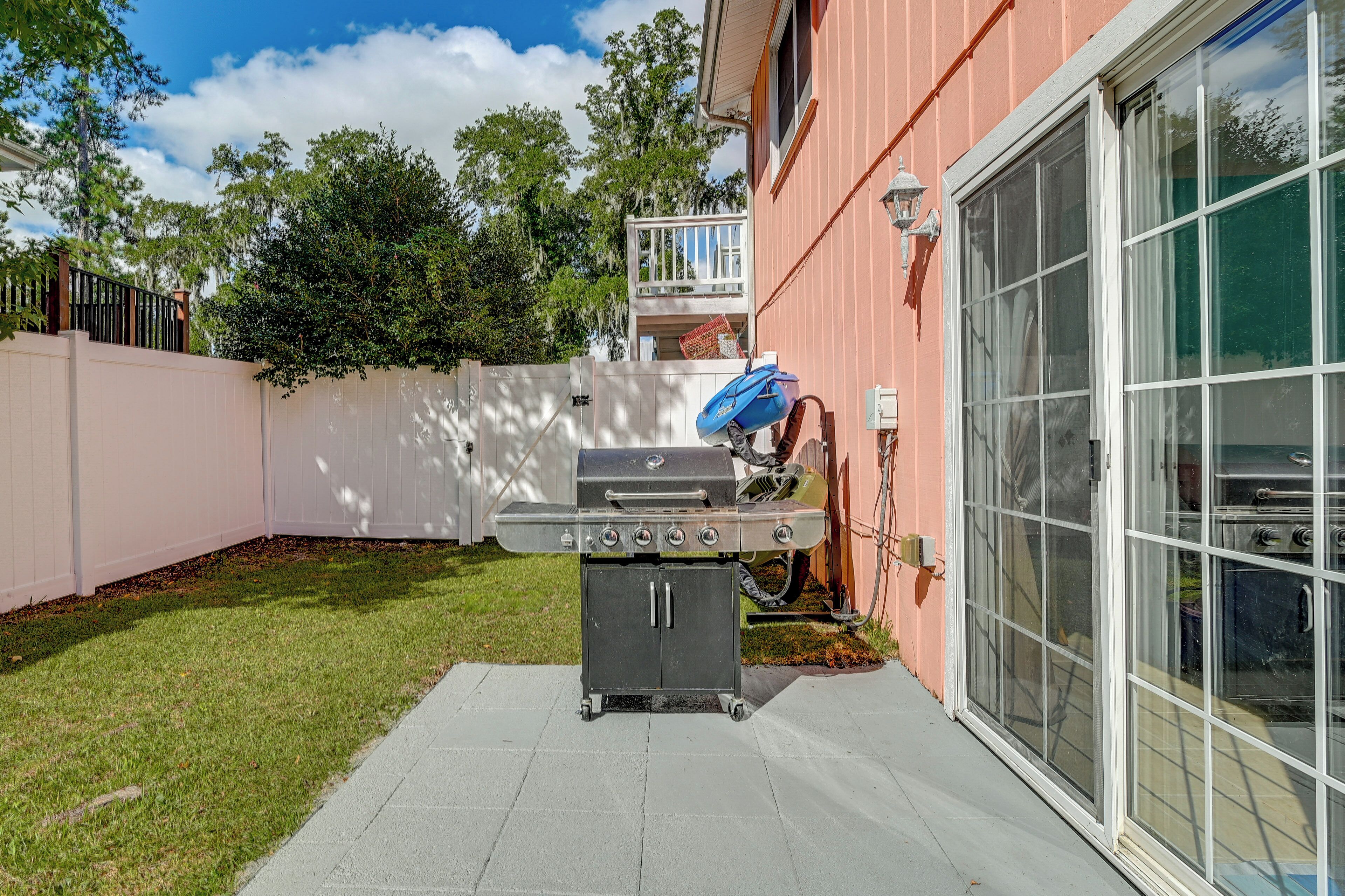 Ein Garten mit einem Grill, einer Glasschiebetür und einem rosafarbenen Haus.