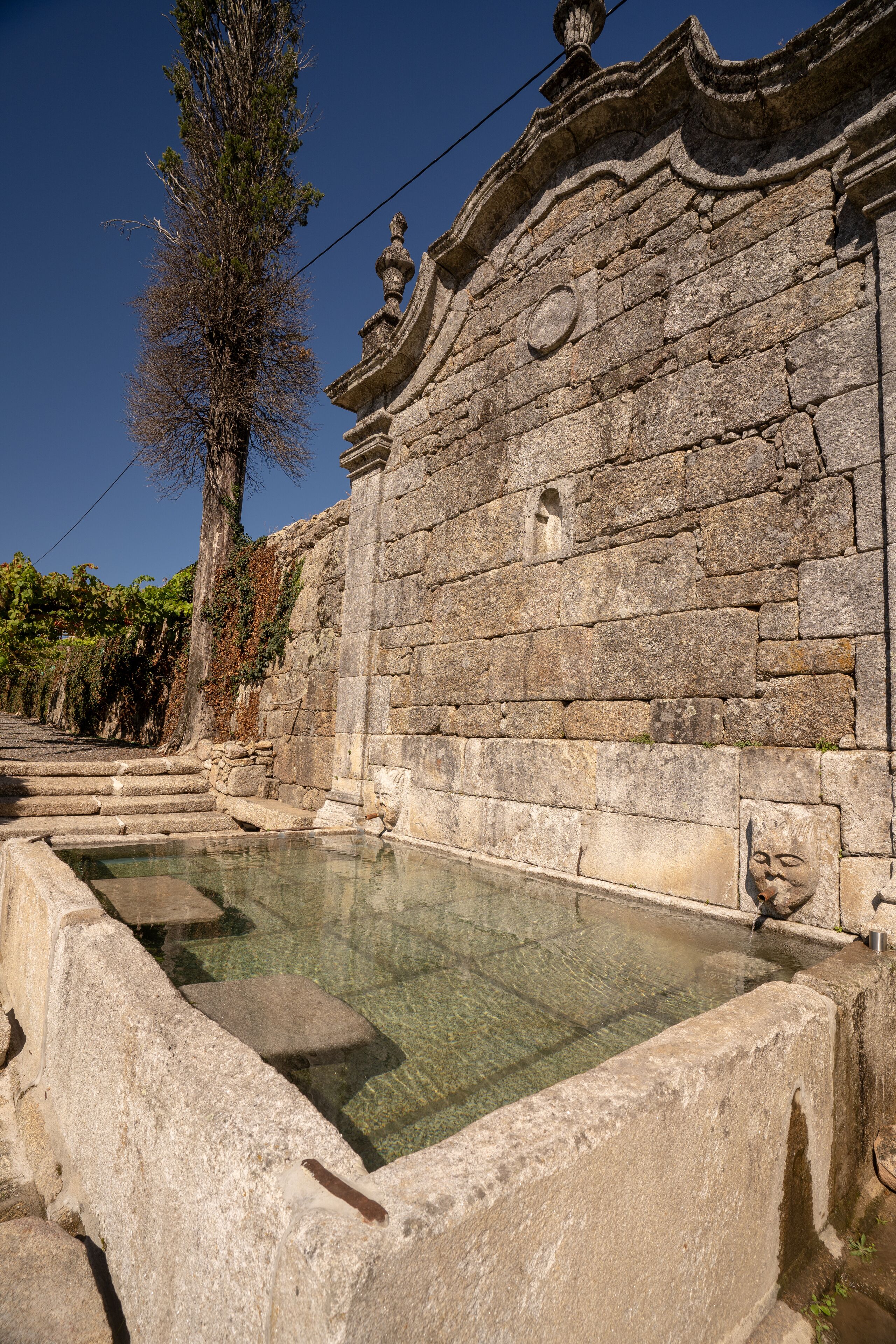Ein altes Steinhaus mit einem klaren Pool davor.