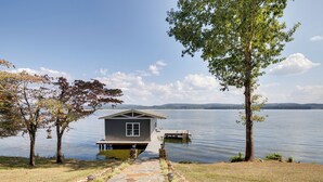 Un chalet au bord du lac, avec un sentier de pierres menant à un quai.