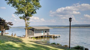 Une maison au bord du lac, avec un quai, un lampadaire et une vue sur le lac et les collines lointaines.