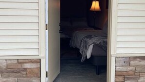 A doorway leading to a bedroom with a bed and a nightstand.