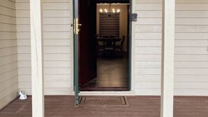 A wooden door leading to a dining area with a chandelier.