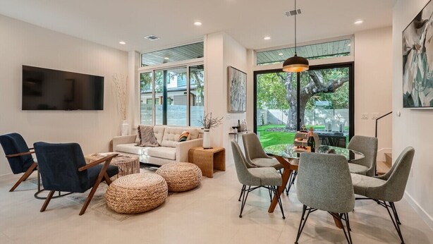 A modern living room with a sofa, chairs, a dining table, and a TV mounted on the wall. - Custom New Build Central Austin Home Mins to DT (Austin)