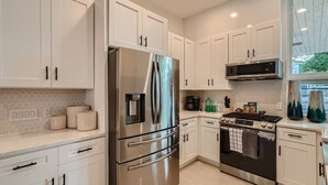 A modern kitchen with white cabinets, stainless steel appliances, and a tiled backsplash. - Custom New Build Central Austin Home Mins to DT (Austin)