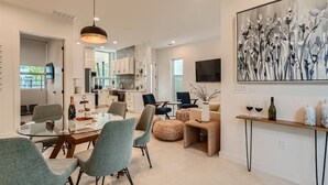 A modern kitchen with white cabinets, a dining area with a glass table and chairs, and a living area with a sofa and a coffee table. - Custom New Build Central Austin Home Mins to DT (Austin)