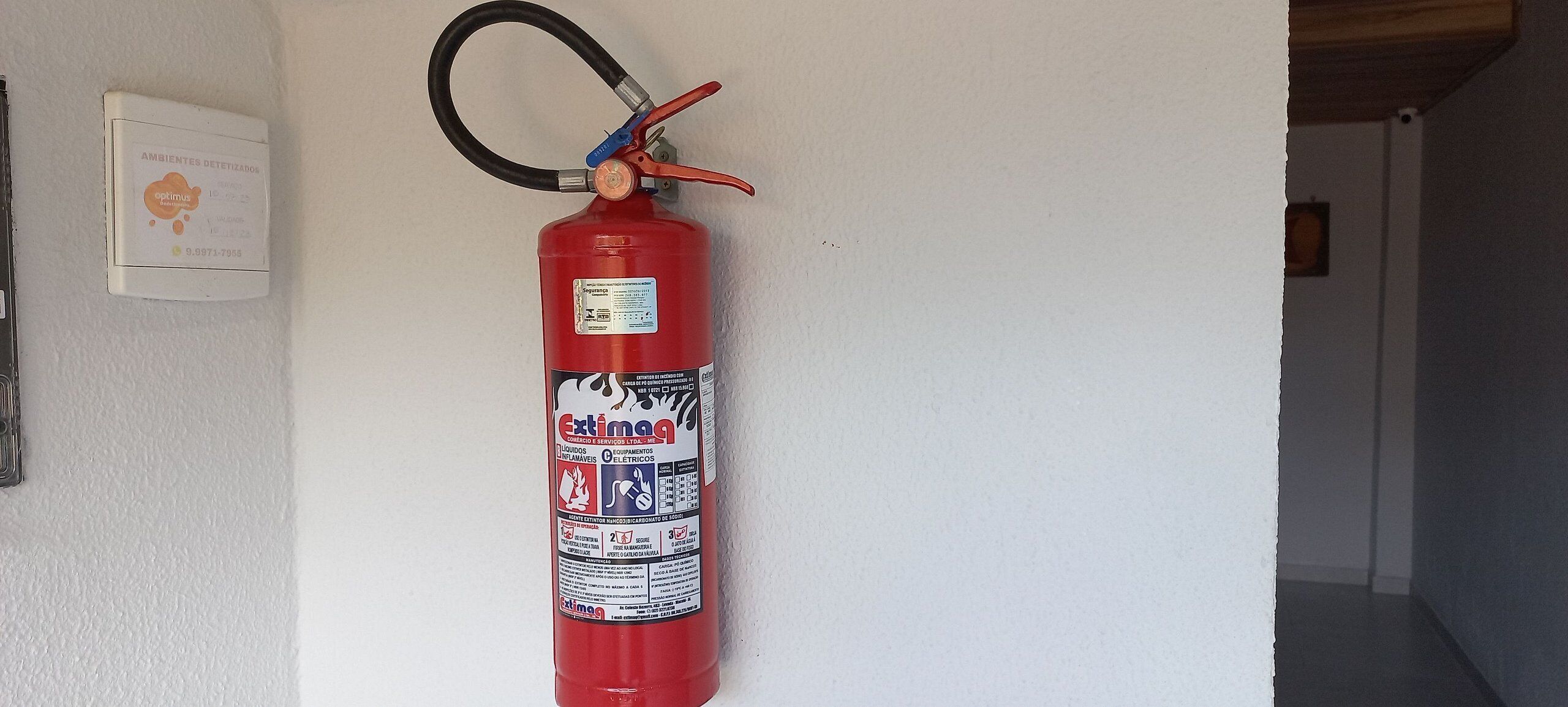 A red fire extinguisher mounted on a white wall.