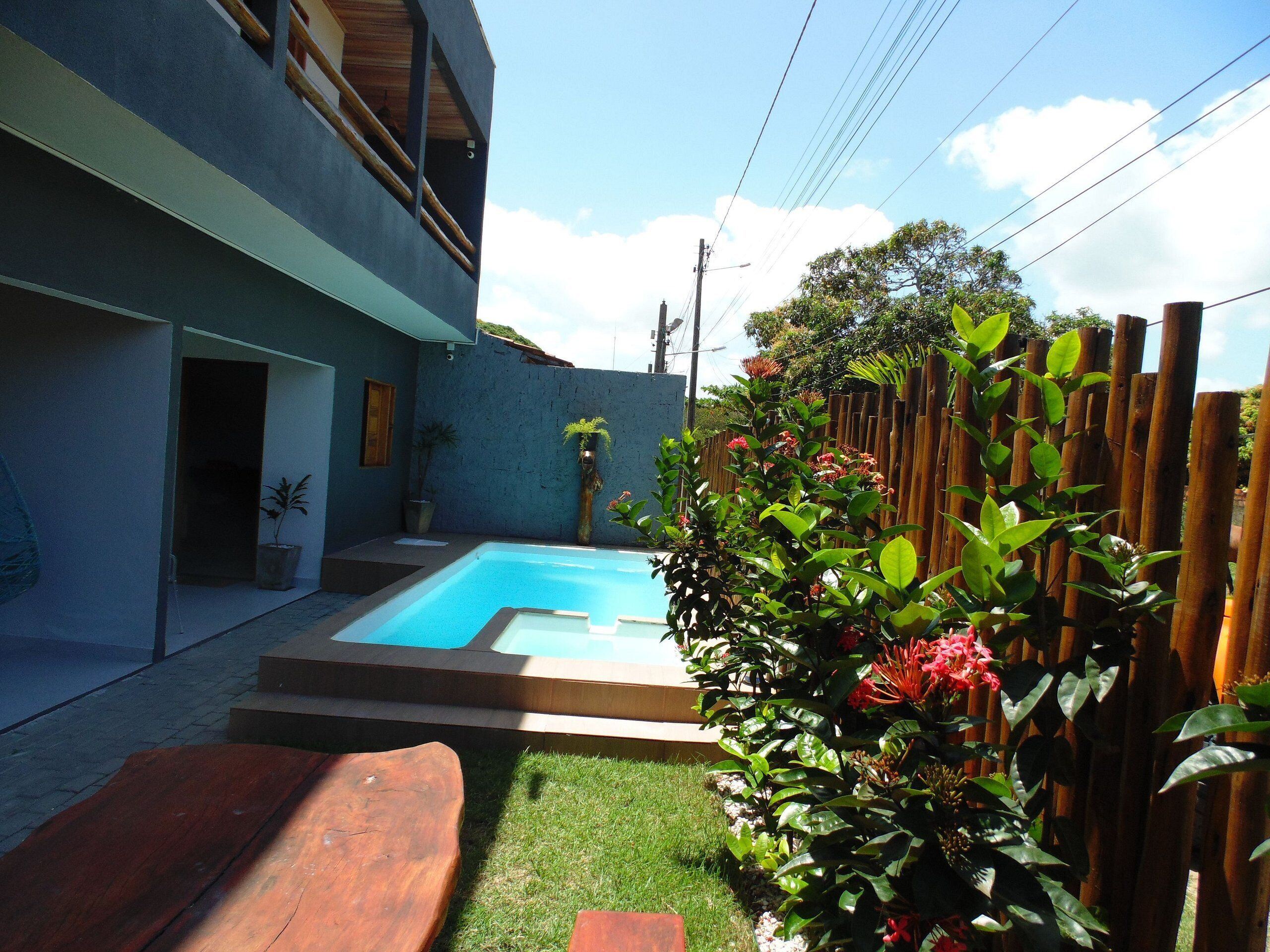 Una casa moderna con piscina, terraza de madera y jardín cercado.