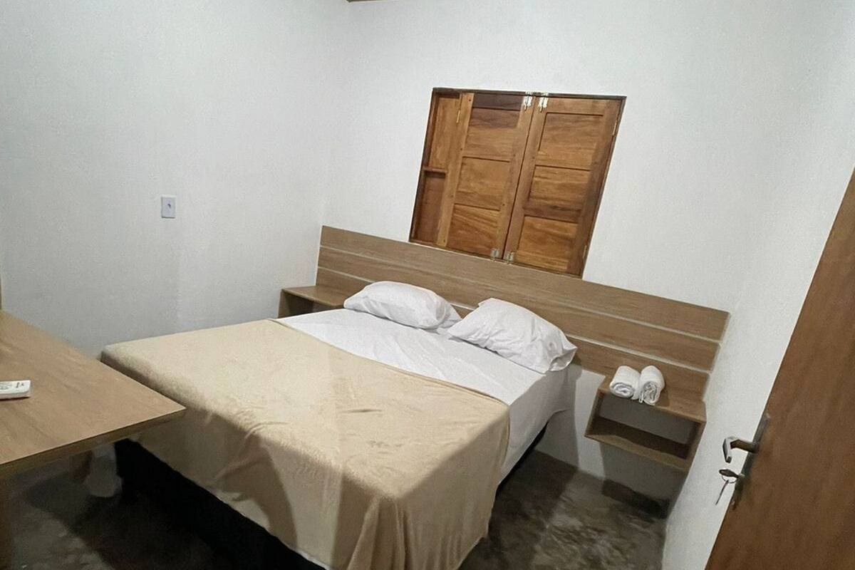 A bedroom with a bed, bedside table, and a wooden wardrobe.