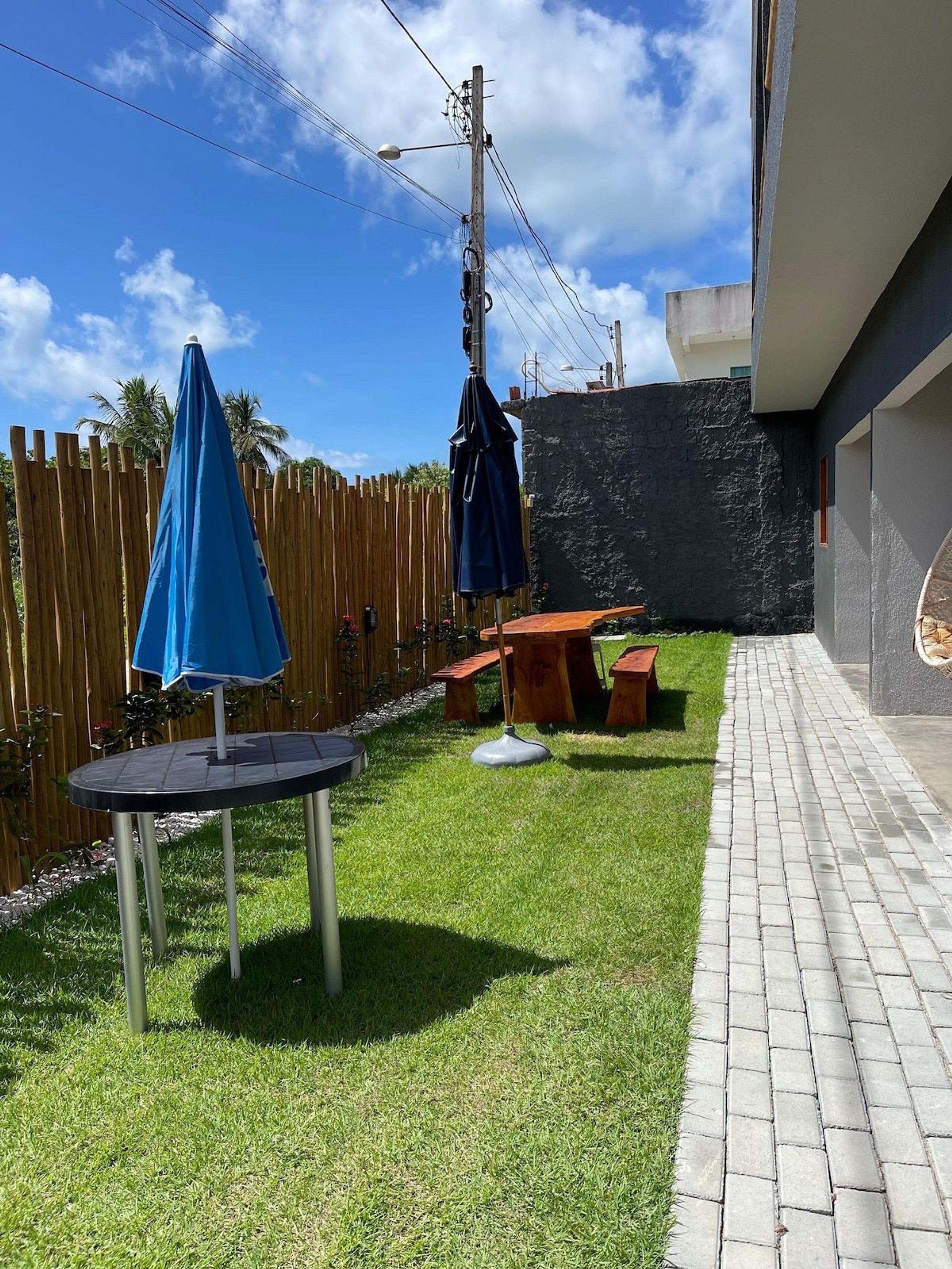 A backyard with a wooden fence, a paved walkway, and outdoor furniture including a table and chairs.