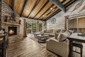 A spacious living room with a fireplace, a large sofa, and a dining table.