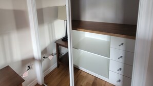 Un dressing accessible sans porte, doté de portes coulissantes, d’un plancher en bois et d’un luminaire fixé au plafond.