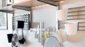 Cozinha com utensílios pendurados, um suporte para panelas e uma janela com vista para o verde.