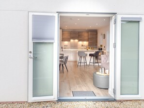 Une cuisine moderne avec des meubles en bois, un coin repas doté de tabourets de bar et un espace détente avec un pouf rond.