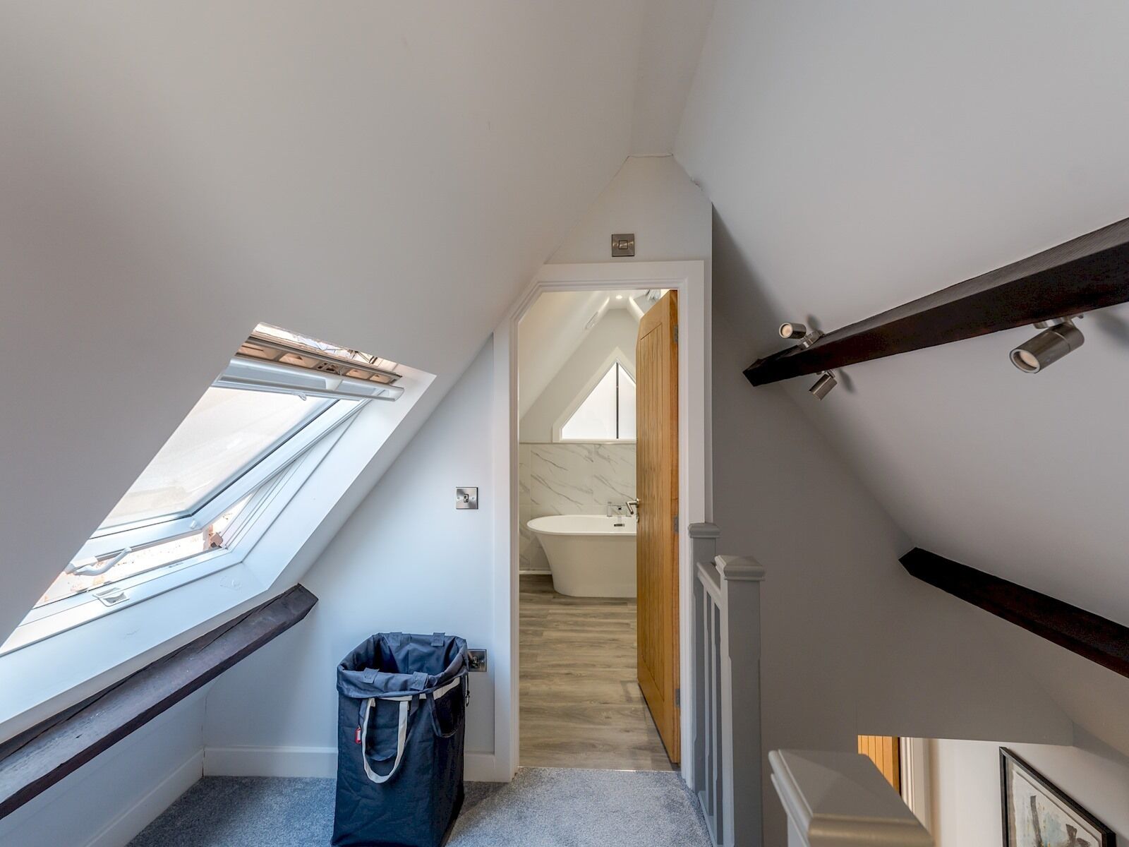 A narrow stairway leading to a bathroom with a skylight and a trash bin.