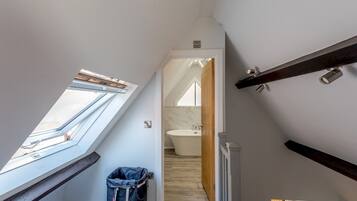 A narrow stairway leading to a bathroom with a skylight and a trash bin.