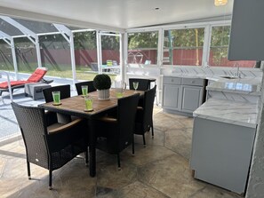 A covered patio area with a dining table, chairs, and a small kitchen area with a sink. - Backyard Oasis, calm, quiet and peaceful. Just pack and come enjoy. (Port St. Lucie)