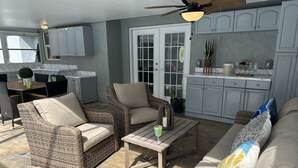 A patio area with wicker furniture, a ceiling fan, and a kitchen in the background. - Backyard Oasis, calm, quiet and peaceful. Just pack and come enjoy.  (Port St. Lucie)