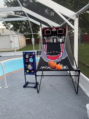 A basketball hoop with a scoreboard and a game list stand beside a pool. - Backyard Oasis, calm, quiet and peaceful. Just pack and come enjoy. (Port St. Lucie)