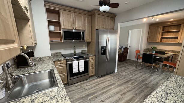 A kitchen with granite countertops, stainless steel appliances, wooden cabinets, and a dining area with a table and chairs. - Backyard Oasis, calm, quiet and peaceful. Just pack and come enjoy.  (Port St. Lucie)
