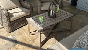 A patio area with wicker furniture, a wooden table, and a glass of drink. - Backyard Oasis, calm, quiet and peaceful. Just pack and come enjoy.  (Port St. Lucie)