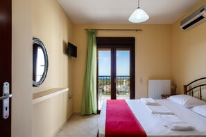 Habitación de hotel con cama, vistas al mar, balcón y ventana con cortinas.
