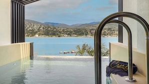 A view from a balcony with a pool, overlooking a body of water and distant hills. - CASALY HOTEL & SPA (Kefalonia)