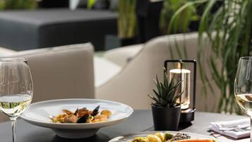 A dining table with plates of food, glasses of wine, and a lit candle centerpiece.